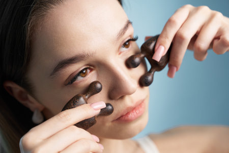 Woman using a facial massage tool for relaxation and skincare at homeの写真素材