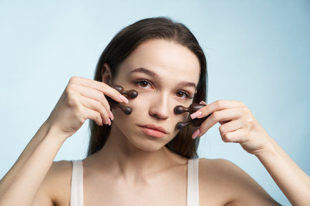 Woman performing facial massage with massage tools in bright settingの写真素材