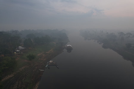 Misty morning view of a river in the Amazon rainforest with canoesの写真素材