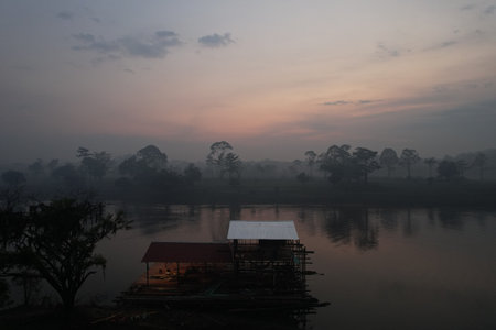Early morning mist rising over the river with a wooden structure nearbyの写真素材