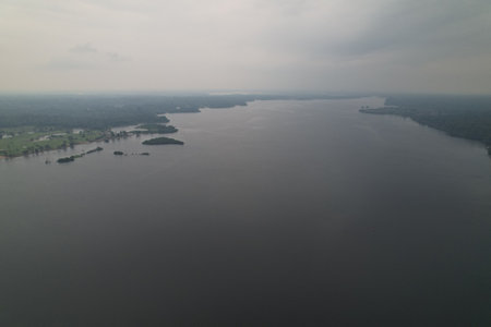 Cloudy sky over a calm river flowing through a lush landscapeの写真素材