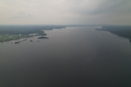 Expansive view of a tranquil river with distant islands under cloudy skiesの写真素材