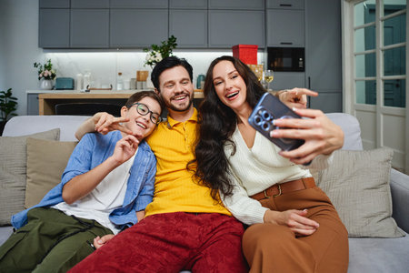 Family enjoying a playful moment together while taking a selfie indoorsの写真素材