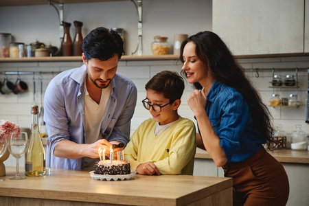 Family celebration with a birthday cake and candles in a cozy kitchenの写真素材