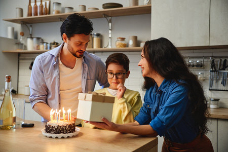 Family celebration with birthday cake and presents in a cozy kitchenの写真素材