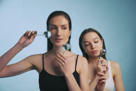 Women practicing skincare techniques with facial tools in a serene settingの写真素材