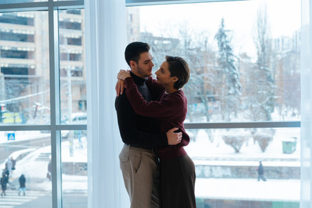 Couple embraces warmly inside bright, modern space during winter season