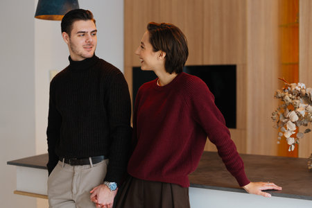 Couple enjoying time together in cozy sweaters at modern kitchenの写真素材
