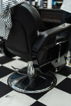 Classic black barber chair set against a checkered floor in a stylish barbershopの写真素材