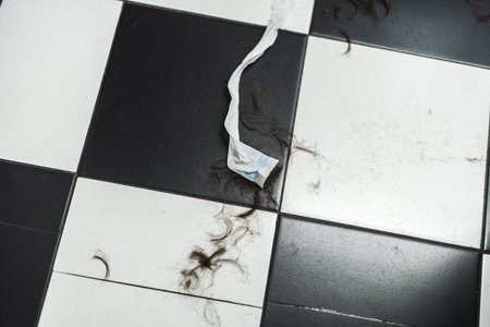 Hair and debris scattered on a stylish black and white tiled floorの写真素材
