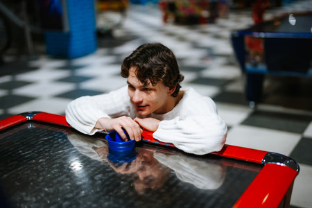 Young man enjoys air hockey at arcade on a lively weekend evening