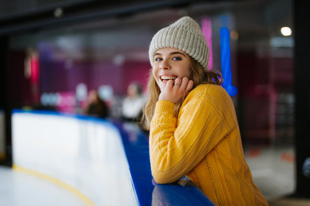 Girl smiling while enjoying time at indoor ice skating rink in winterの写真素材