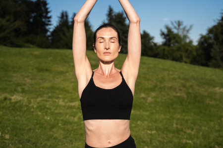 Woman practicing yoga outdoors under a clear blue sky during daytimeの写真素材
