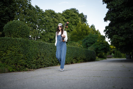 Confident skateboarder strolls through a lush green park on a sunny day
