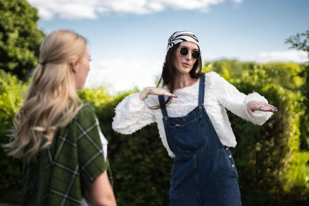 Fashionable women share joyful moment outdoors in stylish outfitsの写真素材