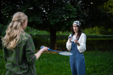 Two friends enjoying a playful badminton match in a lush green parkの写真素材