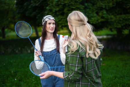 Friends enjoying a sunny day outdoors playing badminton and sharing snacksの写真素材