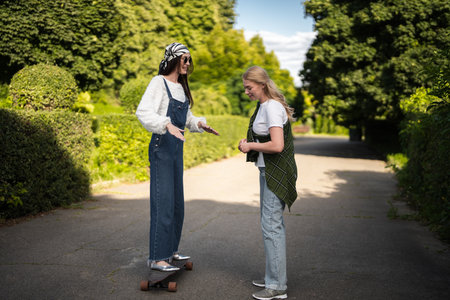 Two friends enjoy a sunny afternoon practicing skateboarding tricks togetherの写真素材