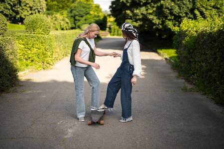 Friends enjoying a sunny day while skateboarding in a vibrant parkの写真素材