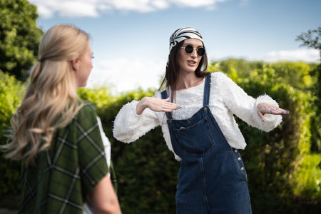 Fashionable friends enjoying a sunny day outdoors while chatting playfullyの写真素材
