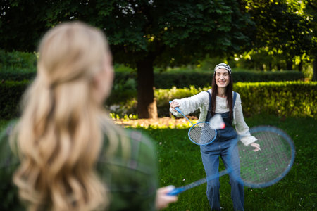 Friends enjoy a lively game of badminton in a sunlit parkの写真素材