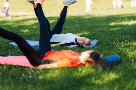 Women exercise on mats in a park during day