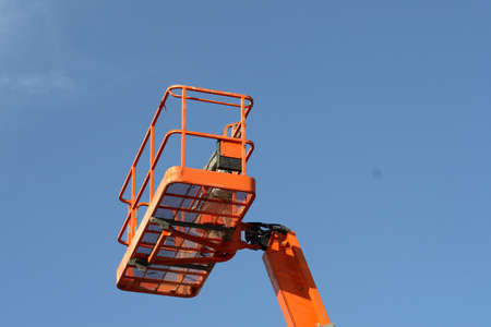 Orange cherry picker crane against a blue skyの写真素材