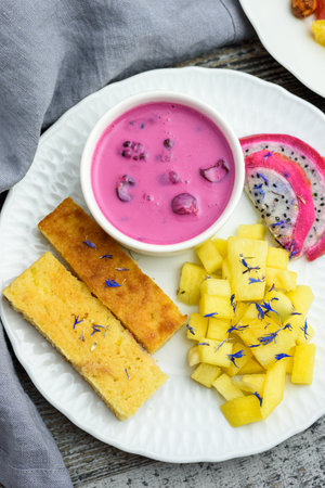 Mango bread with plant-based yogurt and fresh fruits, bright colors, colourful meal, flat layの写真素材