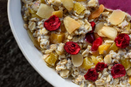 Porridge with chia seeds, almonds, orange pieces, and fruits, flat lay close-up