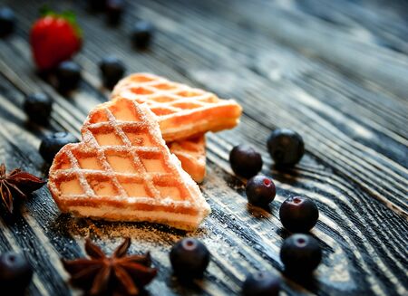 Waffles hearts with blueberry and strawberry tied with a string on the dark wooden background. Dark Valentines day background - heart. Food background.のeditorial素材