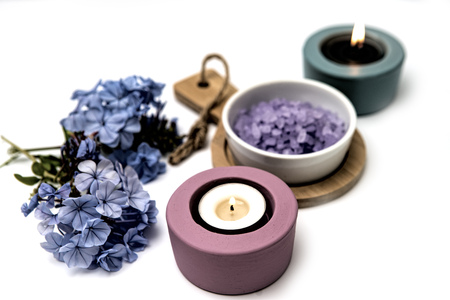 Beautiful spa composition .  Blue flowers and candlelight on a white background