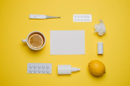 Pills, medical thermometer, nose spray and lemon. Different medications on yellow background. Cold and flu home remedies. Disease self-treatment concept. Flat lay. Top view with blank space for text.の写真素材