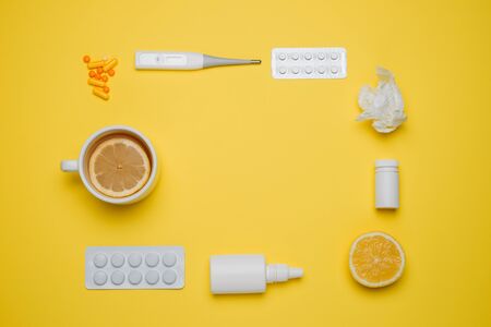 Pills, medical thermometer, nose spray and lemon. Different medications on yellow background. Cold and flu home remedies. Disease self-treatment concept. Flat lay. Top view with blank space for text.の写真素材