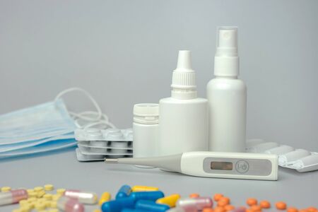 Pills, thermometer and nose spray on gray background. Cold and flu treatment set. Disease treatment concept. Plastic medicine container for tablet, capsule. Close up.の写真素材