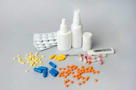 Pills, thermometer and nose spray on gray background. Cold and flu treatment set. Vitamin pill package. Plastic medicine container for tablet, capsule. Top view.の写真素材