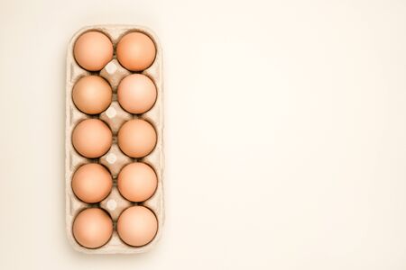A tray of brown fresh hen's eggs on beige background. Eco-friendly egg production. Baking ingredients. Organic chicken eggs - fresh from producer. Top view. Free space for text.の写真素材