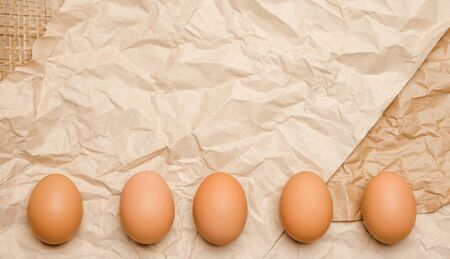 Fresh brown hen's eggs on wrinkled kraft paper. Eco-friendly egg production. Bakery ingredients....