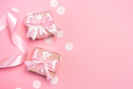 Two gifts or present boxes decorated with confetti and ribbon on pink pastel background. Top view with copy space. Flat lay composition for birthday or wedding.の写真素材