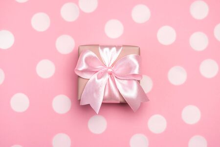 Gift box or present decorated with confetti and robbon on pink pastel background. Top view with copy space. Flat lay composition for birthday or wedding.の写真素材