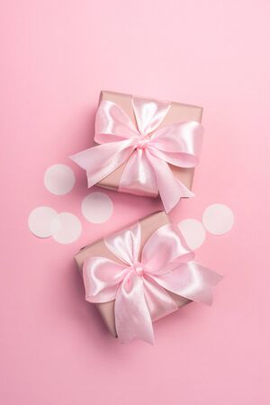 Two gifts or present boxes decorated with confetti on pink pastel background. Top view. Flat lay composition for birthday or wedding. Vertical orientation.の写真素材