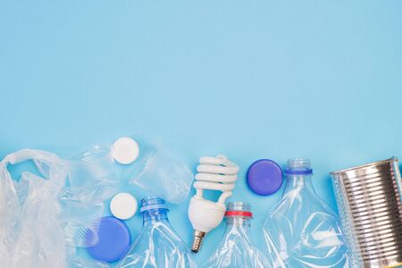 Different types of garbage on blue background. Sorting waste and recycling concept. Ecology and...