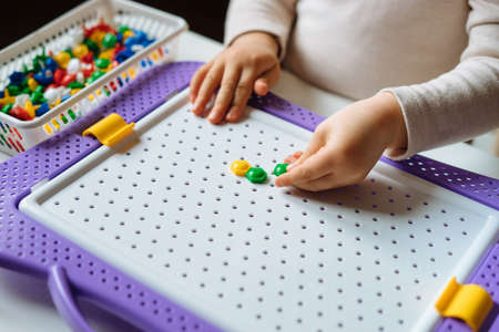 Child is playing with mosaic puzzle at home. Children's creative game for early development and fine motor skills. Fun activities for toddlers. Close up.の写真素材