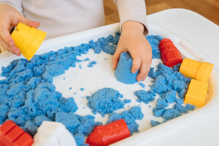 Close view of child's hands playing with kinetic sand. Children's creative game for early development and fine motor skills.の写真素材
