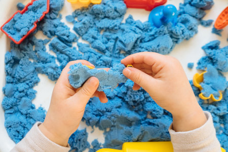 Close view of child's hands playing with kinetic sand. Children's creative game for early development and fine motor skills.の写真素材