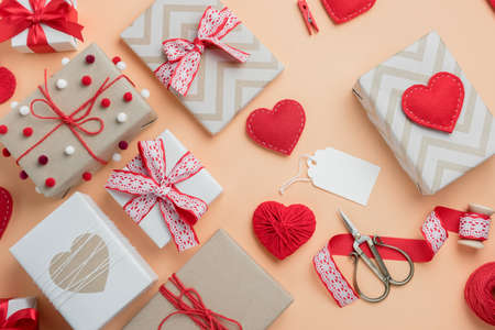 Valentine's Day composition with gifts and handmade hearts on beige background. Top view with blank tag for text.の写真素材