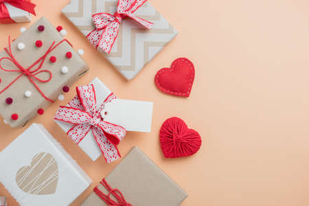Valentine's Day composition with gifts and handmade hearts on beige background. Top view with blank tag for text.の写真素材