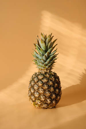 Pineapple with hard trendy shadow on pastel yellow background.