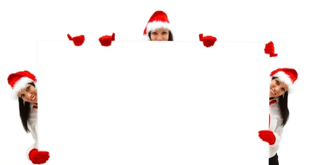 Three female Santas with red hat and gloves over a white billboardの写真素材