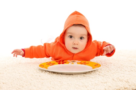 Funny baby girl with a colorful plateの写真素材