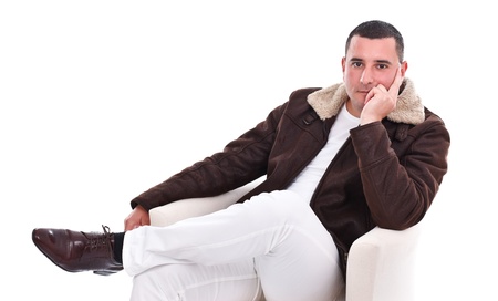 Portrait of a handsome young man sitting in armchair, studio shotの写真素材
